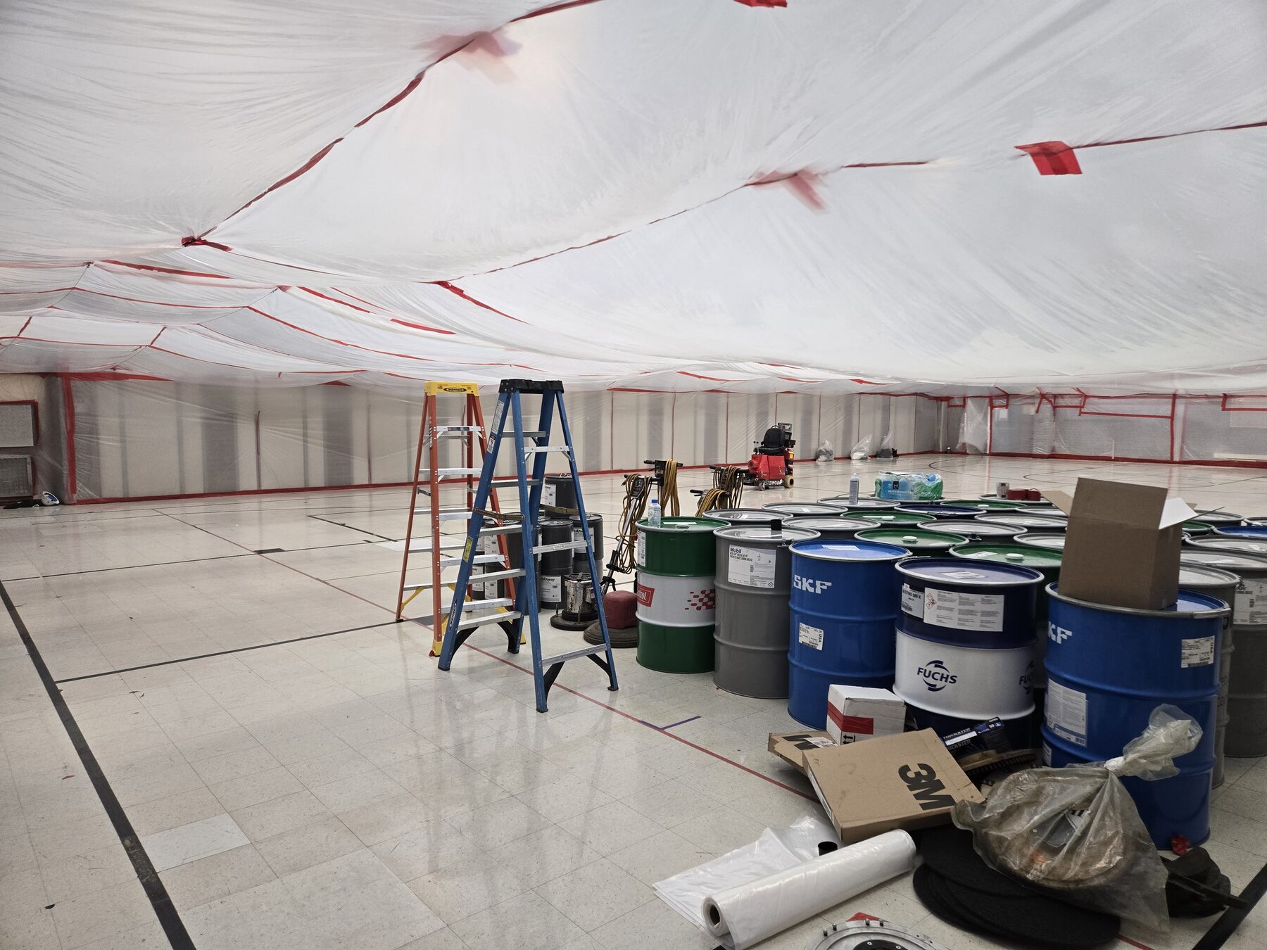Sealed work area with staged abatement materials and waste drums inside a commercial building